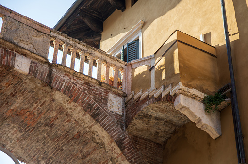 This is an arched bridge connecting two buildings in Verona with adjoining steps at the entrance to the Piazza delle Erbe