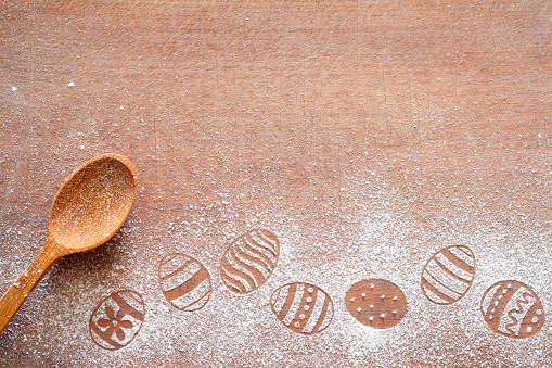Easter eggs made of flour on chopping board with wooden spoon, easter baking background concept, copy space creative
