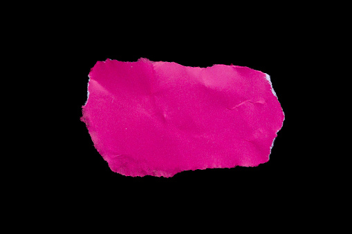 Ripped pink paper piece isolated on black background. Torn paper.