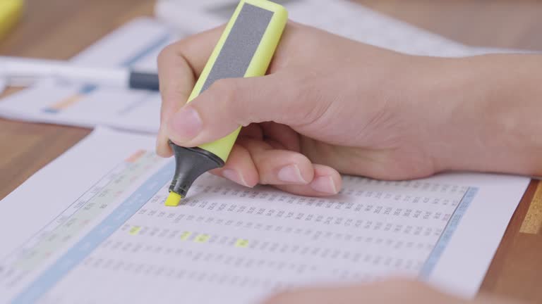 Close up man hands  with a highlighter highlighting the data, calculate monthly Income and expenses, home finances report  document balance