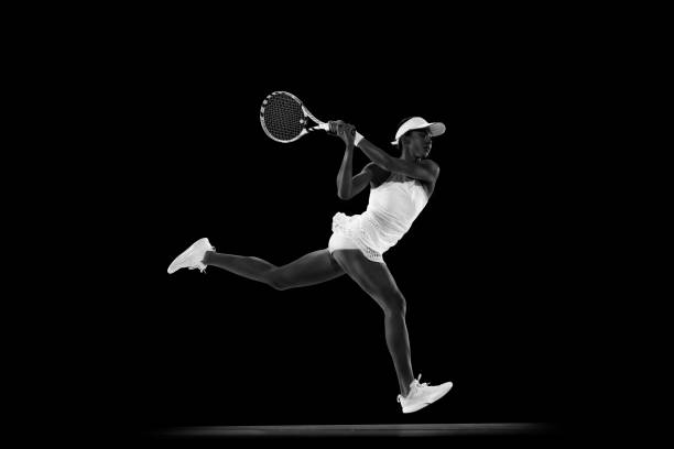 istock Focused athlete in tennis gear executing powerful forehand swing against black studio background. Monochrome filter. 2039647708