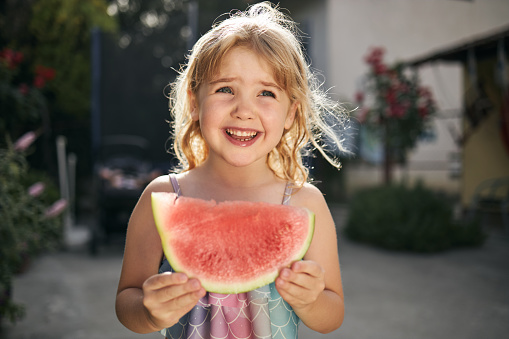 Beautiful girl enjoying summer eating watermelon in back yard.