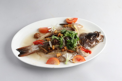 teo chew steamed whole fresh red grouper fish in salted vegetable tomato sauce chinese banquet halal seafood menu on white background