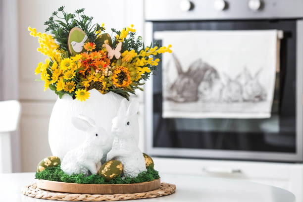 istock A spring bouquet in an egg, Easter bunnies and eggs with a golden pattern on the table. In the background is a white Scandinavian-style kitchen. A beautiful greeting card. Easter decor in the house. 2039704880