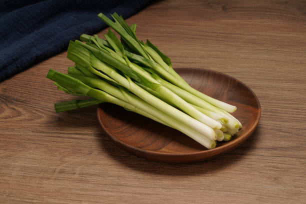 A pile of green onions on a wooden plate stock photo