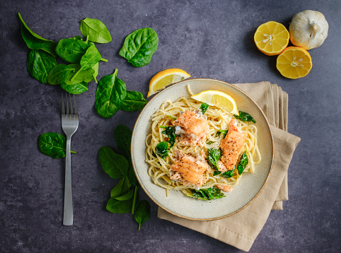 Italian cuisine: spaghetti with salmon, cream and spinach close-up on plate on table. top view.