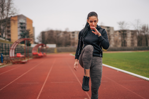 Image of a young woman doing exercises. On a running track.