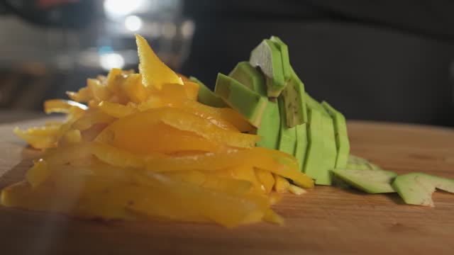 Chef cutting avocado with kitchen knife on cutting board