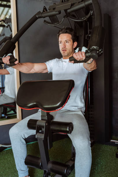 istock Young handsome man exercising with training machine at gym 2039728214