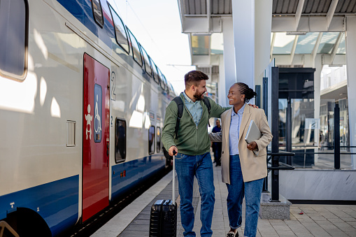 The image shows a Caucasian man and an African American woman who have just stepped off the train, now walking together towards the station exit