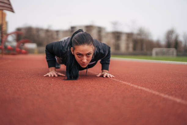 Young sportswoman doing push-ups, on a running track.