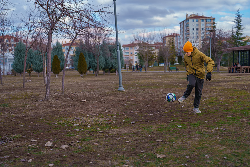 Sibling Playing Football in Public Park in Autumn