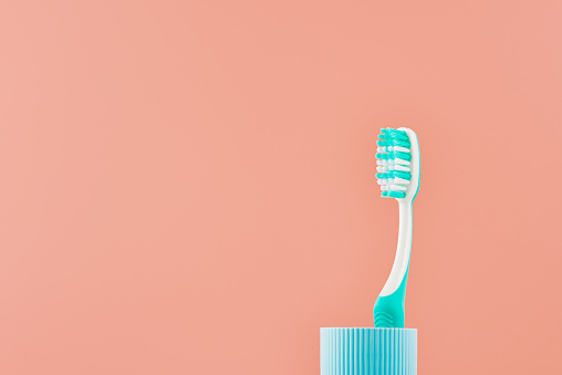 Manual toothbrush on a pink background with copy space. Front view from low angle.