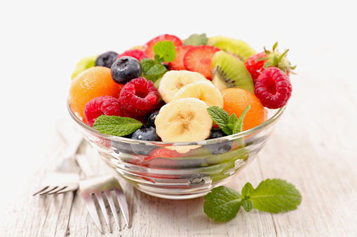 fresh fruits salad with berries, banana and kiwi- nutrition, vegetarian food, health food concept