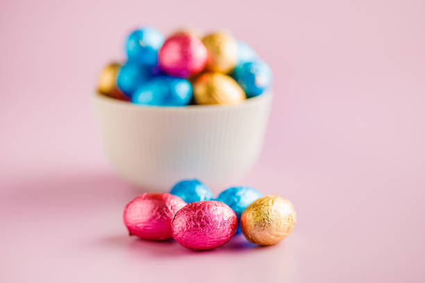 Easter chocolate eggs wrapped in aluminium foil on the pink background.