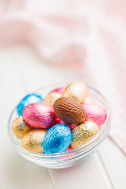 Easter chocolate eggs wrapped in aluminium foil in bowl on the white table.