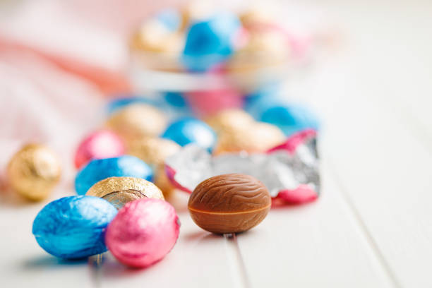 Easter chocolate eggs wrapped in aluminium foil on the white table.
