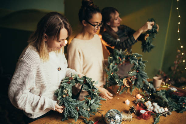 istock Happy women making Christmas wreath using natural pine branches and festive decorations. 2039786177