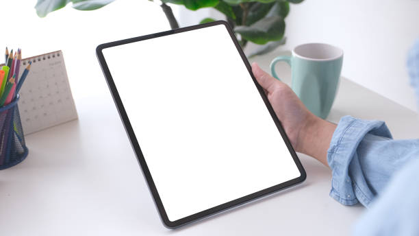 Close up of man hand holding digital tablet with blak screen on working table background for mock up, template