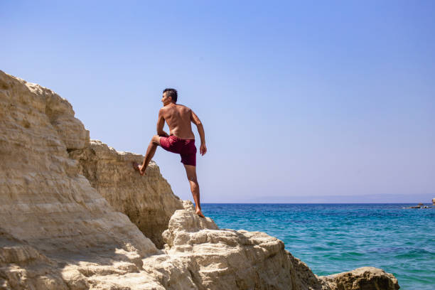 Man standing on top of cliff above sea