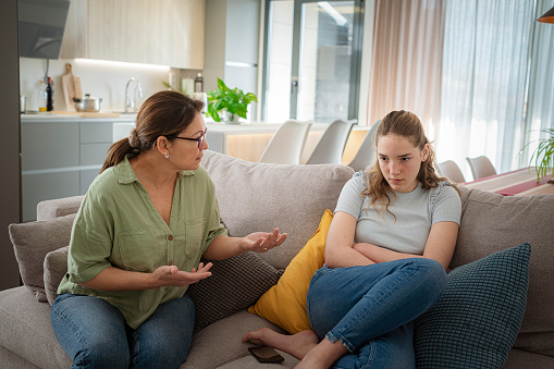 Mother talking to offended adolescent daughter. High resolution 42Mp indoors digital capture taken with SONY A7rII and Zeiss Batis 40mm F2.0 CF lens