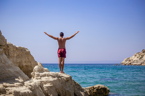 Man standing on top of cliff above sea