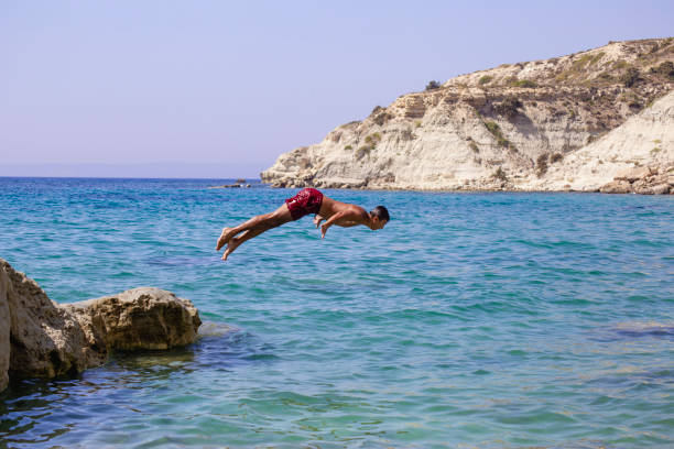 istock Young man jumping into the water from the cliff. 2039839292