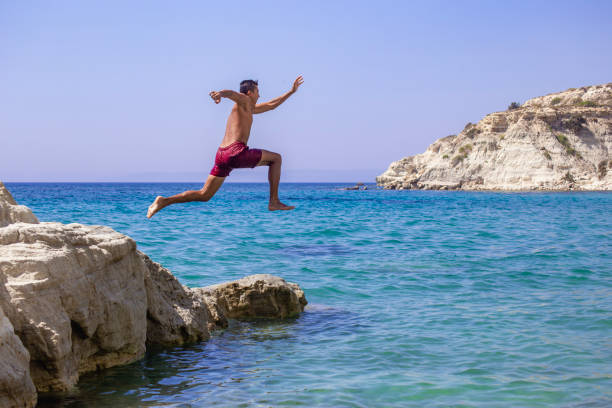 istock Young man jumping into the water from the cliff. 2039839802