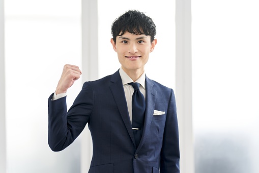 A businessman wearing a custom suit and doing a fist pump