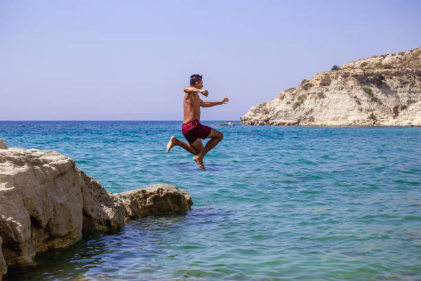 istock Young man jumping into the water from the cliff. 2039840355