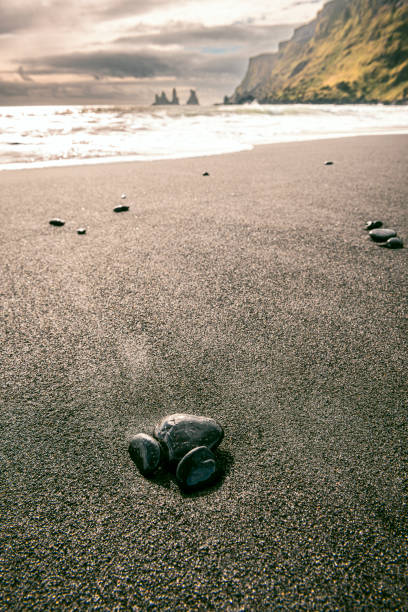 Pebbles on the black basalt sand beach near the village of Vik in Iceland during a sunset in summer.