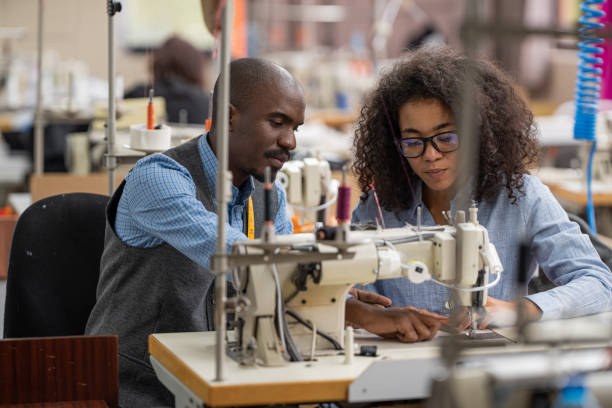 workers in an industrial garment factory sew clothes on sewing machine