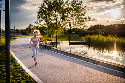 Music, running, blonde woman, enjoys jogging in natural surroundings