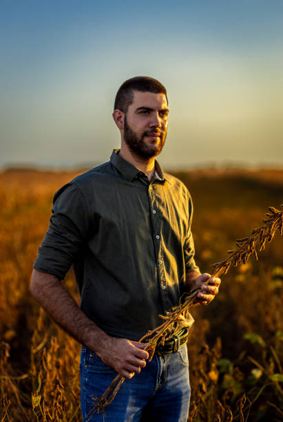 istock Young farmer standing in a soy field examining crop before harvest. 2039898620