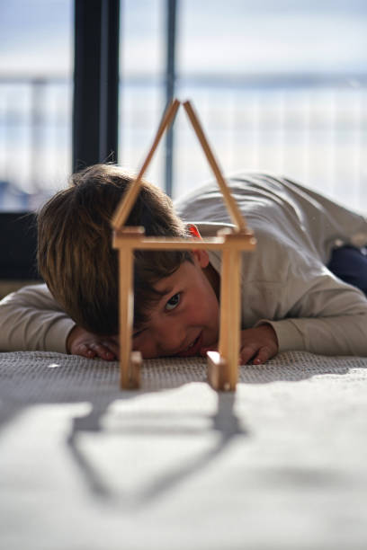 istock A child looking through a wood toy house. 2039899698