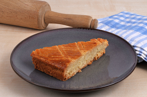 Portion of traditional Breton cake on a plate with a rolling pin and a tea towel close-up