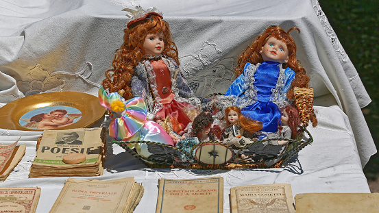 Naples, Italy - June 22, 2014: Vintage Dolls Toys and Old Books for Sale Antique Market at Promenade Lungomare Sunday.