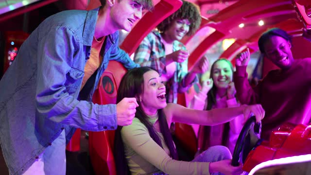 group of multiracial friends having fun playing video arcade and dancing in a night room with neon lights