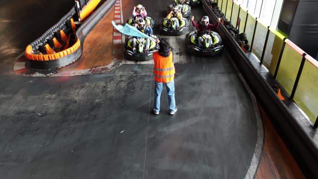 Go kart racer all prepared for the start, woman with starting flag, race on the circuit with electric cars.