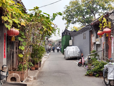 People walking at a Beijing's Hutong, a type of narrow street or alley commonly associated with northern Chinese cities, especially Beijing.\nIn Beijing, hutongs are alleys formed by lines of siheyuan, traditional courtyard residences.