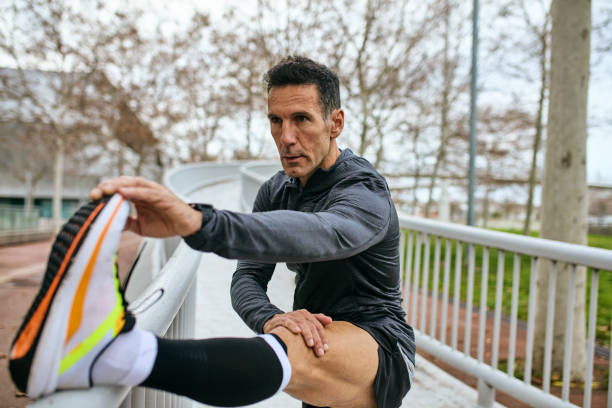 focused sportsman stretching before running - railing beautiful human leg people imagens e fotografias de stock