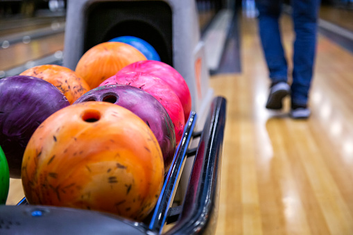 Bowling alley with balls and people in background, selective focus