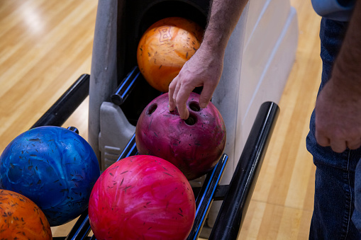 Close-up of a man's hand choosing bowling ball in a bowling club.