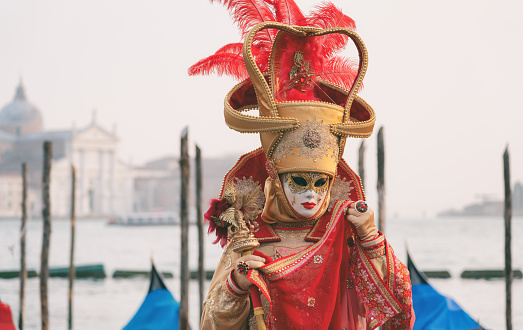 Venice, Italy - February 26, 2017: Carnival Mask with beautiful Venice Lagoon and gondola in the background at sunset