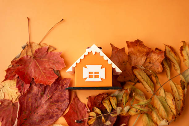 istock Dry maple leaves around miniature orange house on orange background 2040031833