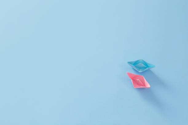 istock pink and blue paper boats on blue background 2040057529