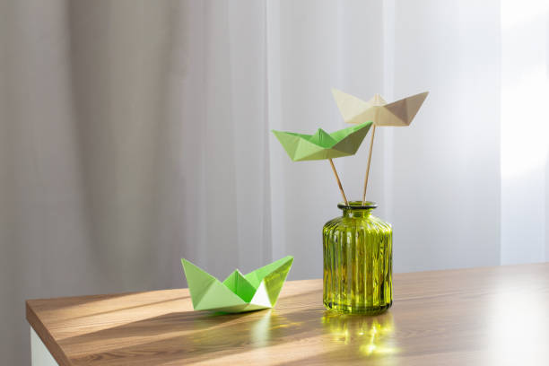 bateaux en papier dans un vase en verre vert sur une table en bois - nautical vessel isolated toy boat wood photos et images de collection