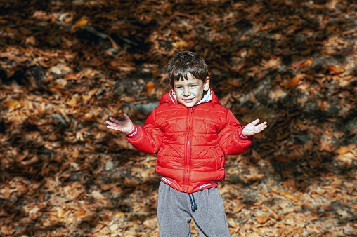 Portrait of boy in red coat with open hands