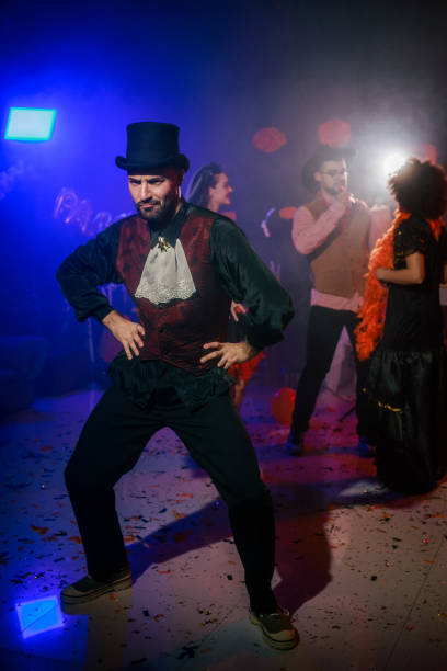 istock Young man in a costume and a top hat dancing during a Halloween party 2040109760