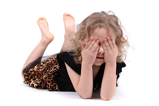 The little girl lay down on the floor and closed her eyes on a white background.